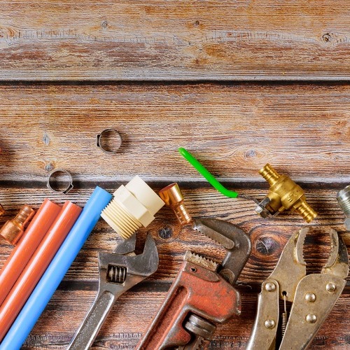 a variety of plumbing tools on a wooden surface